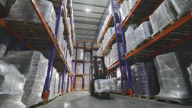 The forklift is driving through the warehouse of the factory. Modern warehouse. Large warehouse in the factory. Warehouse work
