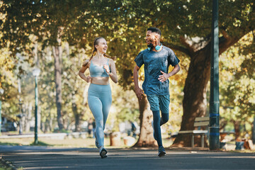 Fototapeta premium Running, exercise and fitness with a diversity couple in the park for a cardio workout together. Training, motivation and run with a man and woman athlete bonding while exercising outside in the day