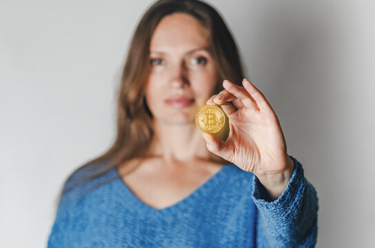 Portrait of woman in casual clothes looking at camera holding bitcoin, future currency, isolated on white background in studio. People lifestyle concept.