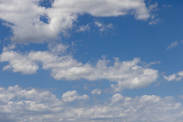 Summer midday pale blue sky with white fluffy lightest clouds torn evenly over it