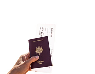 Hand of a woman holding a French passport and Business Class Boarding Pass to go to Dubai against white background