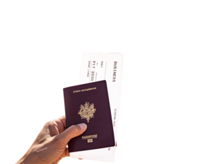 Hand of a woman holding a French passport and Business Class Boarding Pass to go to Dubai against white background