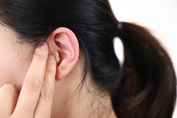 A woman suffering from hearing loss presses her ears with her fingers