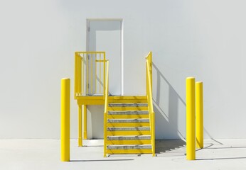 Empty wall of a warehouse with yellow stairs and poles