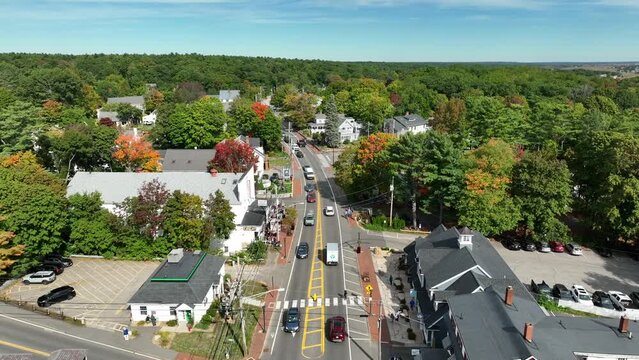 Small town in New England USA during busy daytime shot. Aerial pullback reveals traffic on street along restaurant shopping area.