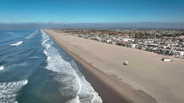 Aerial calm sandy Hollywood beach with foamy waves against a clear blue sky, Oxnard California