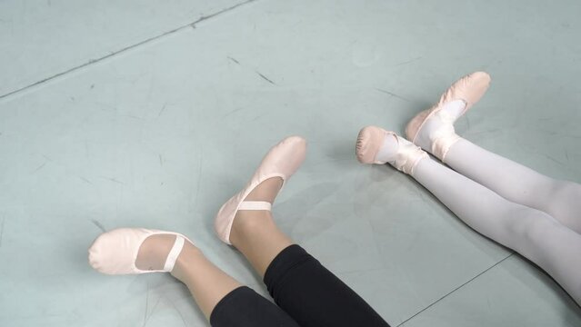 Close up of young ballerinas stretching their legs and feet, training session.