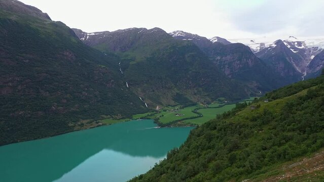 Approaching Indre Yrisetra mountain cottage above Oldevatn lake in Olden Norway - Stunning aerial with unique perspective and the Briksdal glacier in background