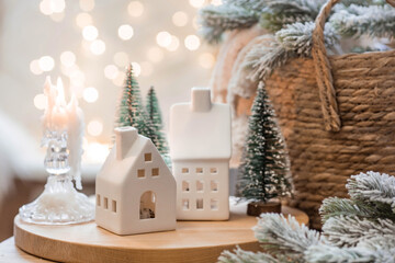 A bouquet of fir trees, a plaid in a wicker basket and Scandinavian white houses on a wooden table...