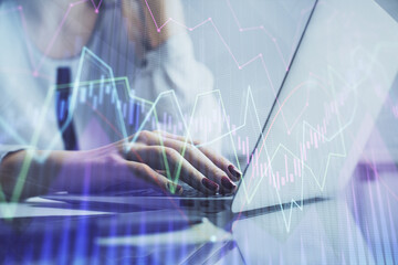 Double exposure of woman hands typing on computer and financial graph hologram drawing. Stock market analysis concept.