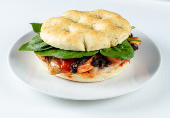 Baguette redondo de beicon con verduras sobre fondo blanco. Round bacon baguette with vegetables on white background.