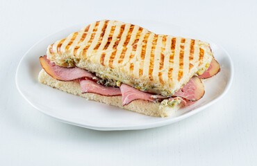 Sándwich a la plancha de jamón con queso fundido sobre fondo blanco. Grilled ham sandwich with melted cheese on white background.