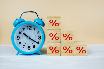 Blue alarm clock and percentages on cubes. Interest rate. inflation, risk management