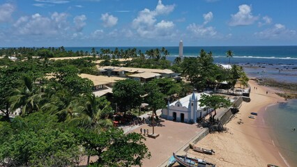 Wonderful view of Praia do Forte beach near Salvador with fishing boats, turquoise waters and a colonial church. Praia do Forte, Bahia, Brazil 