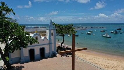 Wonderful view of Praia do Forte beach near Salvador with fishing boats, turquoise waters and a colonial church. Praia do Forte, Bahia, Brazil 
