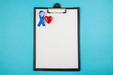 clipboard with sheet of paper blue silk ribbon and small red heart symbol of prostate cancer awareness