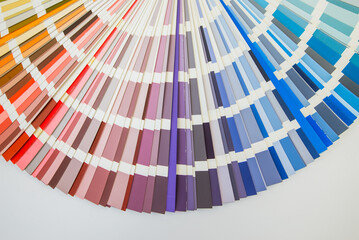 Color guide close up. Assortment of colors for design. Colors palette fan on white concrete wall...