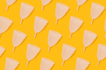 Repetitive pattern made of white menstrual cup on a yellow background. Minimal concept.
