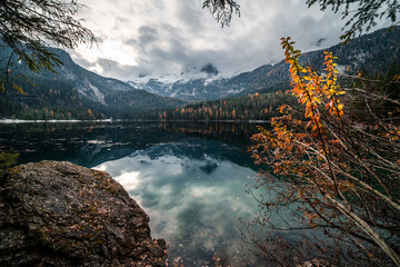 Reflection of the Dolomites peaks in Tovel Lake during a clody autumn day, Northern Italy
