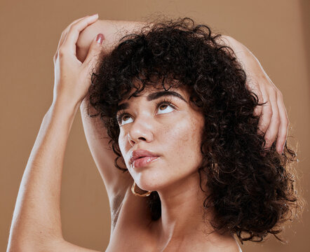 Curly hair, woman and freckles, beauty and makeup for glow, shine and hair care on studio background. Young girl model, melasma face and natural cosmetics, clean skincare and dermatology aesthetics
