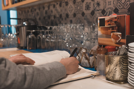 Camarero irreconocible en el restaurante, escribiendo un pedido de comida para llevar a domicilio.