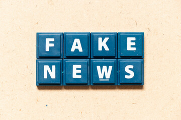 Tile letter in english word fake news on wood background