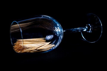 Obraz premium bamboo wooden toothpicks in glass jar, wine glass. in bucket. toothpicks on black background. front view toothpicks, dropped from hand, place for text,