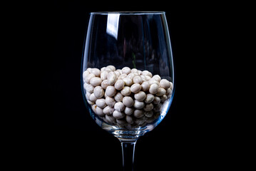 raw white beans in glass jar, wine glass. in bucket. raw white beans on black background. front...
