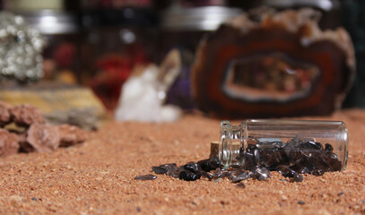 Fototapeta na wymiar Bottle of Chakra Stones on Red Sand With Agatized Coral in Background