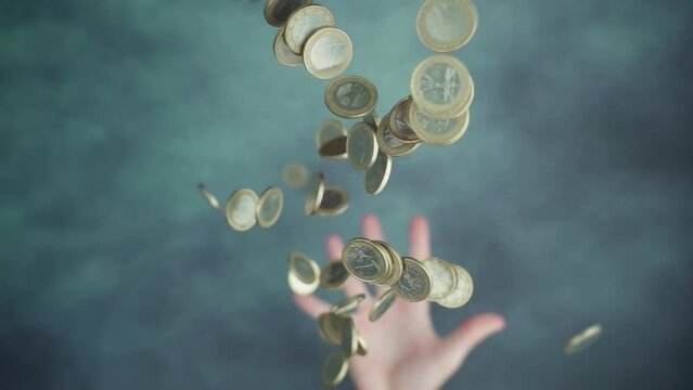 Throwing up handful pile of steel coins above blurred and spotted green-colored table at studio illumination macro slow motion