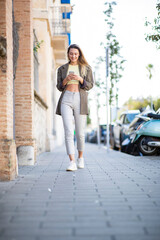 Woman using cellphone while walking outdoors in city