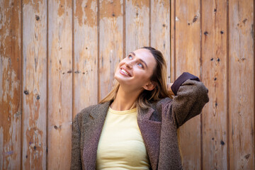 Fototapeta premium Beautiful stylish young woman leaning on wooden door and looking up