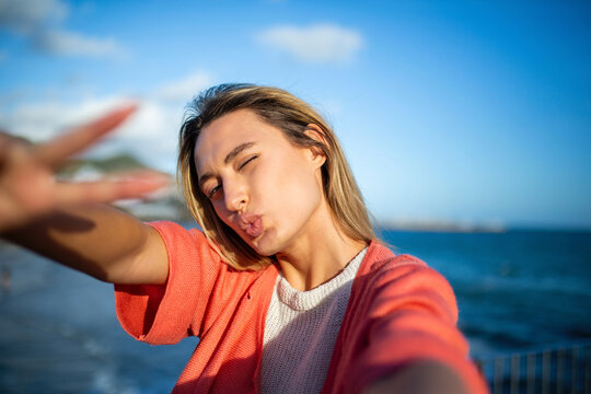 happy young woman taking selfie by sea