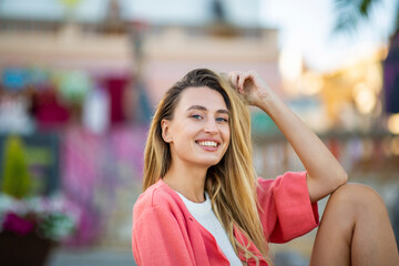 Portrait of happy stylish woman relaxing outdoors with hand in hair