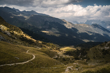 Fototapeta premium Spots of sunlight over the green hills and peaks of the Orobie Alps, Northern Italy