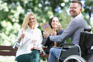 Happy disabled man in wheelchair is learning English with his friends.