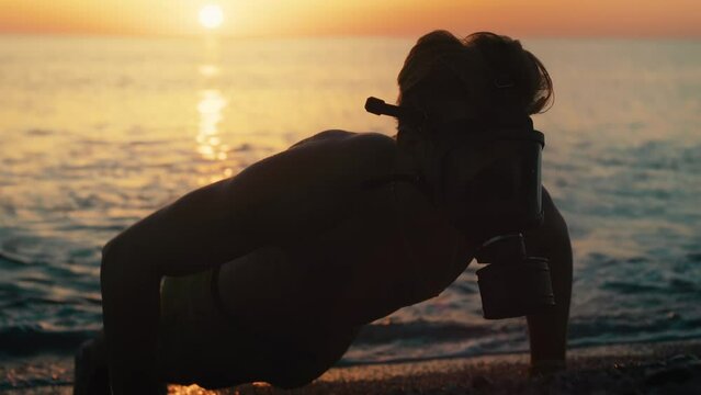man does push-ups in the water with gas mask