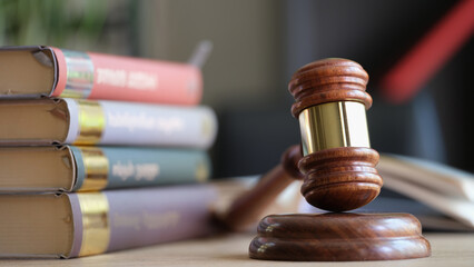 Wooden judge gavel and stack of legal book on table.