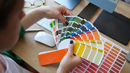 Female designer holding color samples and choosing color samples for projects.