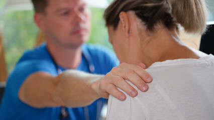 Male doctor supports sad female patient in clinic office.