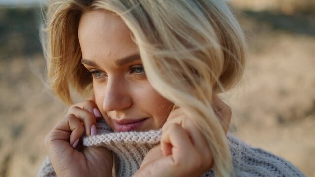 Sweater girl enjoying windy autumn portrait. Hair blowing in blond model face