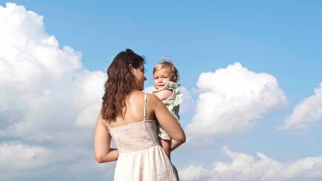Mother holding her daughter in arms outdoors