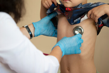 The doctor uses a stethoscope on the boy's stomach to check his health.
