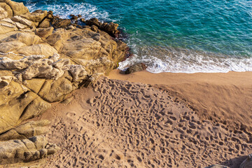 Paisaje de la Costa brava, playa de guijarros cerca del mar con la mano de un niño