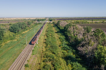 Freight train wagons passing through countryside in the afternoon, Aerial view