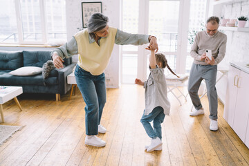 Content mother teaching daughter to dance and father taking photo
