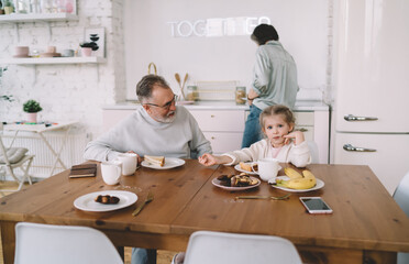 Obraz premium Grandfather talking to granddaughter while grandmother cooking
