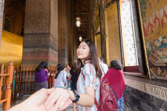 Beautiful asian woman leading man hand to travel in buddhist temple