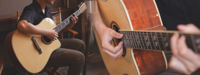 Musician is sitting and playing an acoustic guitar with panorama background. Concept of musical...