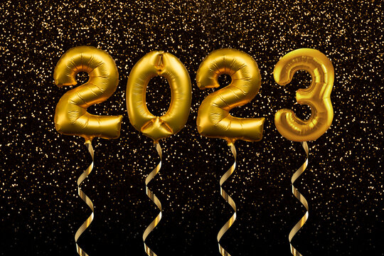 2023 written with golden balloons floating on gold glitter background, new year party greeting card